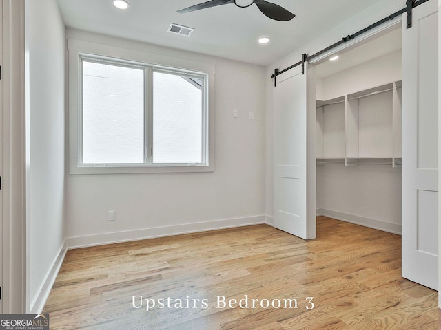 1240 Hayes Sq, Peachtree City, GA 30269 - unfurnished bedroom with a barn door, a closet, recessed lighting, light wood-style flooring, and baseboards