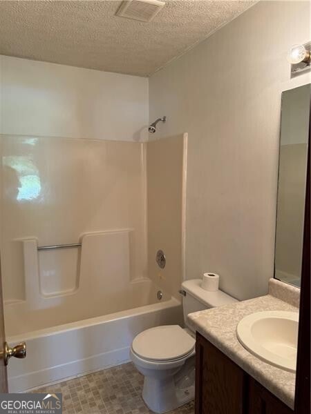 285 Woodland St, Dallas, GA 30157 - bathroom with a textured ceiling, vanity, shower / bathtub combination, and toilet