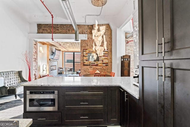87 Peachtree St SW Unit 209, Atlanta, GA 30303 - kitchen featuring light stone countertops, oven, brick wall, and a peninsula