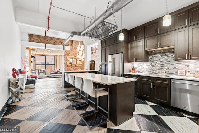 87 Peachtree St SW Unit 209, Atlanta, GA 30303 - kitchen featuring stainless steel appliances, a sink, a breakfast bar area, tasteful backsplash, and dark brown cabinets