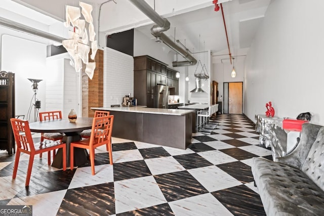 87 Peachtree St SW Unit 209, Atlanta, GA 30303 - kitchen with a peninsula, light countertops, a high ceiling, wall chimney exhaust hood, and dark floors