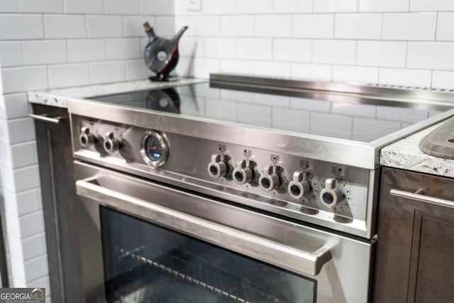 87 Peachtree St SW Unit 209, Atlanta, GA 30303 - kitchen view of stainless steel stove, backsplash, dark brown cabinetry, and light stone countertops