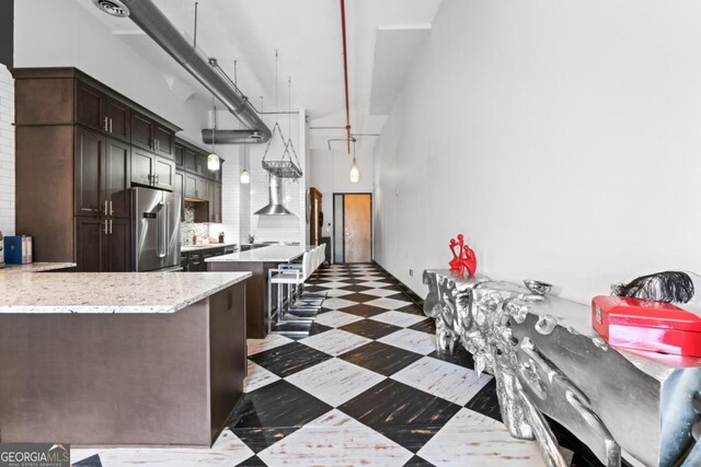 87 Peachtree St SW Unit 209, Atlanta, GA 30303 - kitchen featuring high end refrigerator, a high ceiling, a kitchen bar, dark brown cabinets, and dark flooring