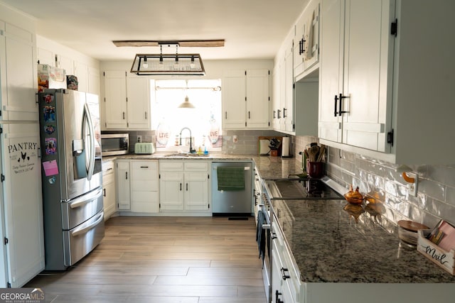 4076 Airline Rd, Mcdonough, GA 30252 - kitchen featuring appliances with stainless steel finishes, a sink, decorative backsplash, light wood finished floors, and dark stone countertops