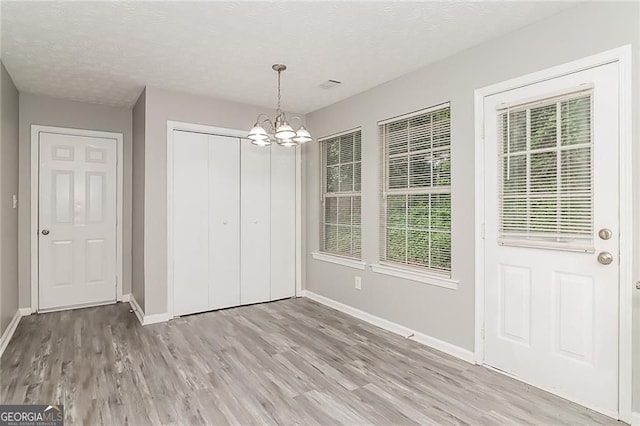 5229 Kirk Dr, Atlanta, GA 30349 - unfurnished dining area featuring a chandelier, light wood-style floors, baseboards, healthy amount of natural light, and a textured ceiling