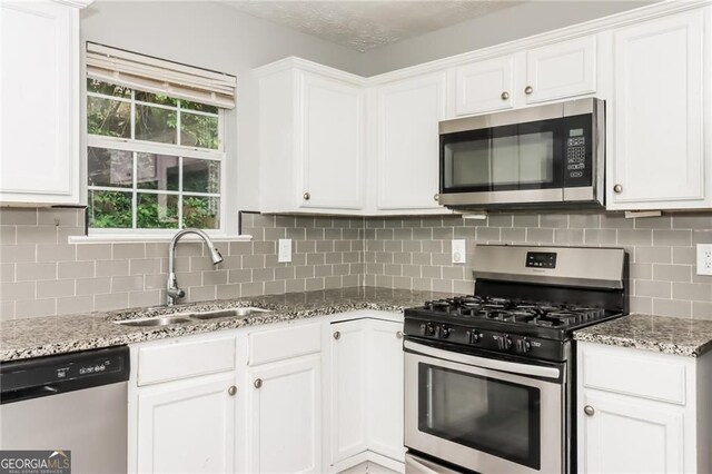 5229 Kirk Dr, Atlanta, GA 30349 - kitchen with stainless steel appliances, a sink, white cabinetry, and light stone counters