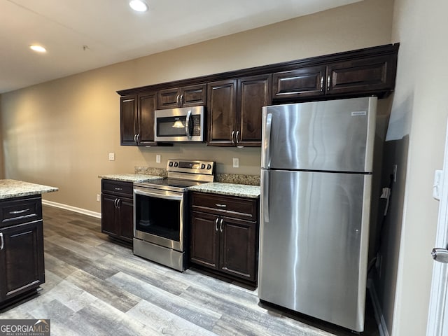 1853 Broad River Rd, Atlanta, GA 30349 - kitchen featuring appliances with stainless steel finishes, light wood-type flooring, recessed lighting, dark brown cabinetry, and light stone counters