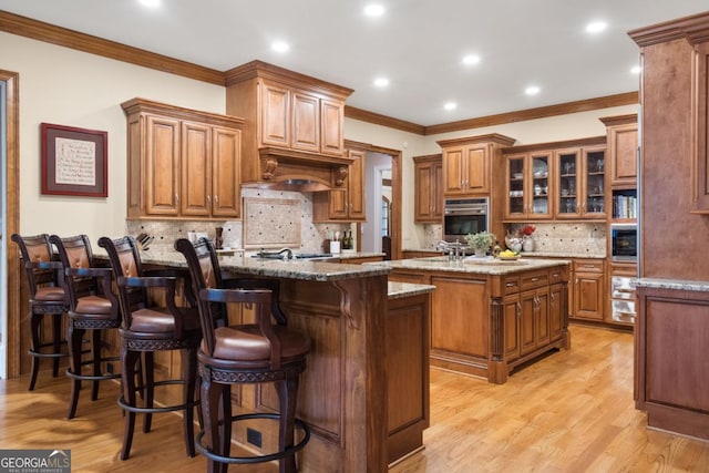 13037 Overlook Pass, Roswell, GA 30075 - kitchen with brown cabinetry, a center island with sink, decorative backsplash, appliances with stainless steel finishes, and a kitchen bar