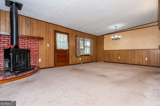 3549 Dogwood Dr, Powder Springs, GA 30127 - unfurnished living room featuring a wood stove, carpet floors, a chandelier, wooden walls, and baseboards