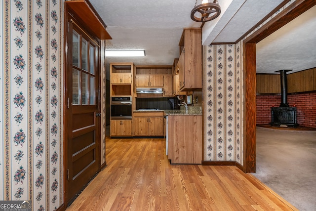 3549 Dogwood Dr, Powder Springs, GA 30127 - kitchen featuring stainless steel oven, a textured ceiling, a wood stove, a sink, and under cabinet range hood