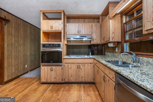 3549 Dogwood Dr, Powder Springs, GA 30127 - kitchen featuring appliances with stainless steel finishes, a sink, under cabinet range hood, light wood finished floors, and light stone counters