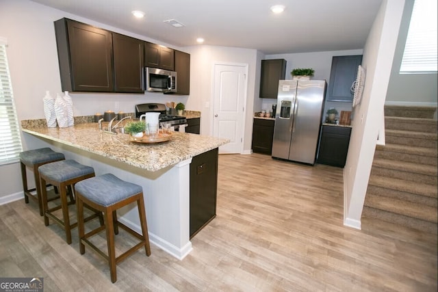 306 Cody Dr, Macon, GA 31216 - kitchen featuring stainless steel appliances, a peninsula, baseboards, a breakfast bar, and light wood finished floors