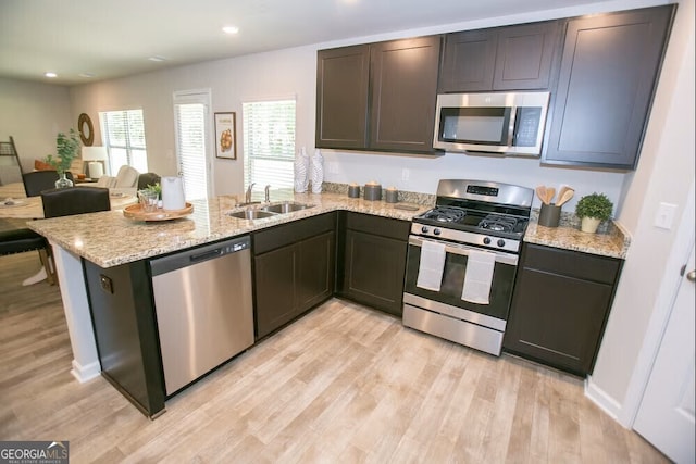 306 Cody Dr, Macon, GA 31216 - kitchen with stainless steel appliances, a sink, light wood finished floors, a peninsula, and light stone countertops