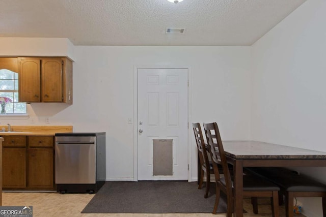 128 Deann Dr, Hinesville, GA 31313 - kitchen with brown cabinetry, a textured ceiling, light countertops, a sink, and dishwasher
