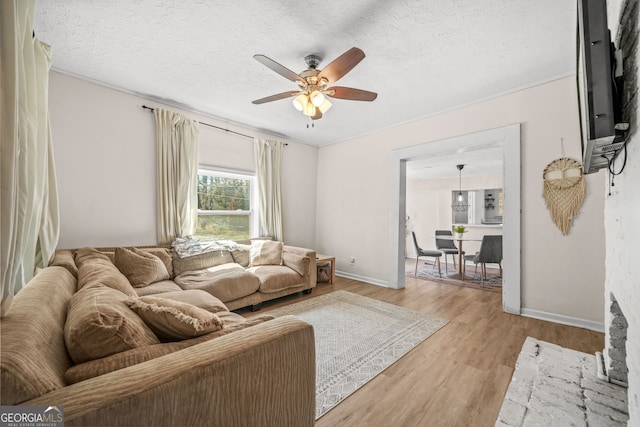 2826 Ben Hill Rd, East Point, GA 30344 - living room featuring a ceiling fan, light wood-style flooring, a textured ceiling, baseboards, and crown molding