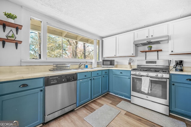 2826 Ben Hill Rd, East Point, GA 30344 - kitchen with stainless steel appliances, blue cabinetry, open shelves, under cabinet range hood, and a textured ceiling