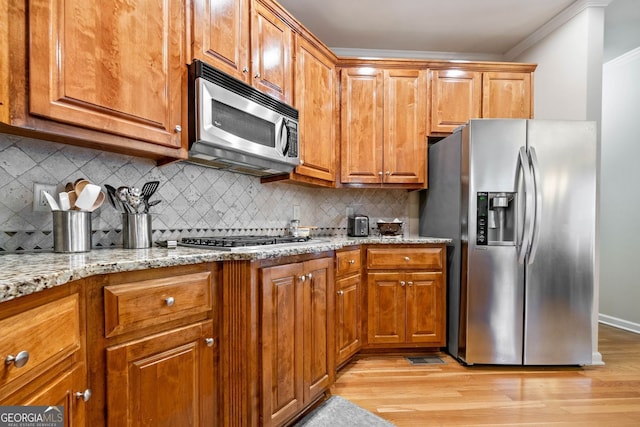 1898 Alcovy Shoals Blf SE, Lawrenceville, GA 30045 - kitchen featuring stainless steel appliances, ornamental molding, light wood-style floors, light stone countertops, and brown cabinets