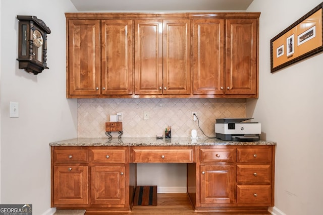 1898 Alcovy Shoals Blf SE, Lawrenceville, GA 30045 - kitchen with tasteful backsplash, light stone countertops, brown cabinetry, and light wood finished floors