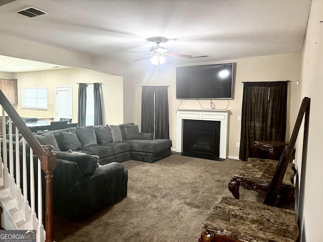 9108 Alden Dr, Locust Grove, GA 30248 - carpeted living room featuring ceiling fan, a fireplace with flush hearth, and stairs