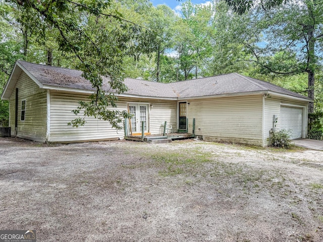 147 Glen Oaks Rd, Perry, GA 31069 - back of house featuring french doors, an attached garage, central AC, a shingled roof, and driveway