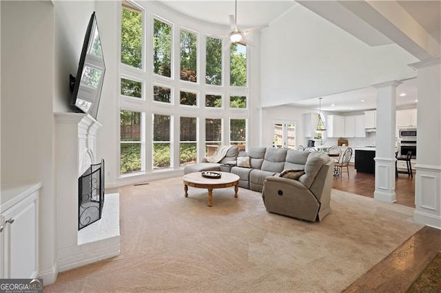 4108 Wyndam Hill Dr, Suwanee, GA 30024 - living area with a fireplace, a high ceiling, decorative columns, a decorative wall, and a ceiling fan