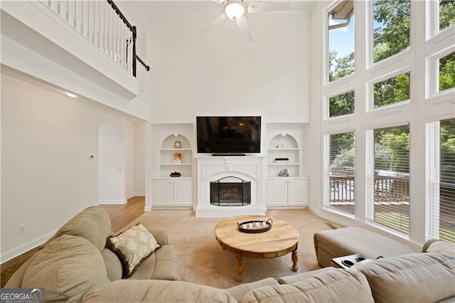 4108 Wyndam Hill Dr, Suwanee, GA 30024 - living room featuring a high ceiling, arched walkways, built in features, ceiling fan, and a brick fireplace