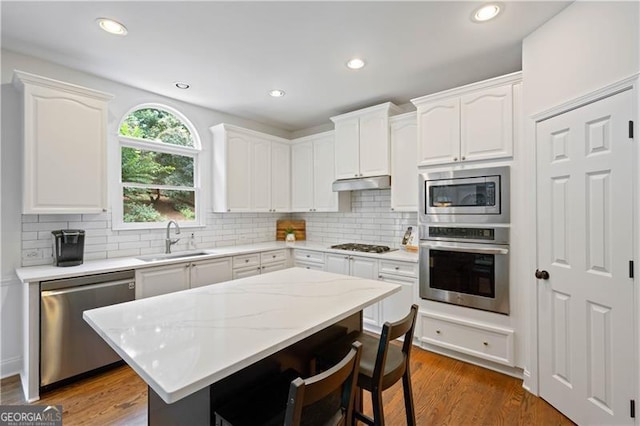 4108 Wyndam Hill Dr, Suwanee, GA 30024 - kitchen with appliances with stainless steel finishes, under cabinet range hood, a kitchen bar, white cabinets, and tasteful backsplash