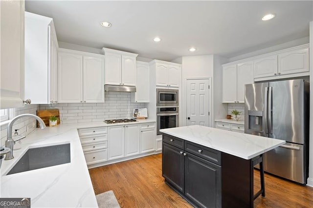 4108 Wyndam Hill Dr, Suwanee, GA 30024 - kitchen with appliances with stainless steel finishes, white cabinets, decorative backsplash, a kitchen breakfast bar, and light stone counters