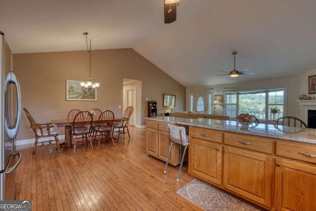 2008 Hidden Valley Rd, Hiawassee, GA 30546 - kitchen with freestanding refrigerator, light wood-style floors, ceiling fan, lofted ceiling, and light stone counters