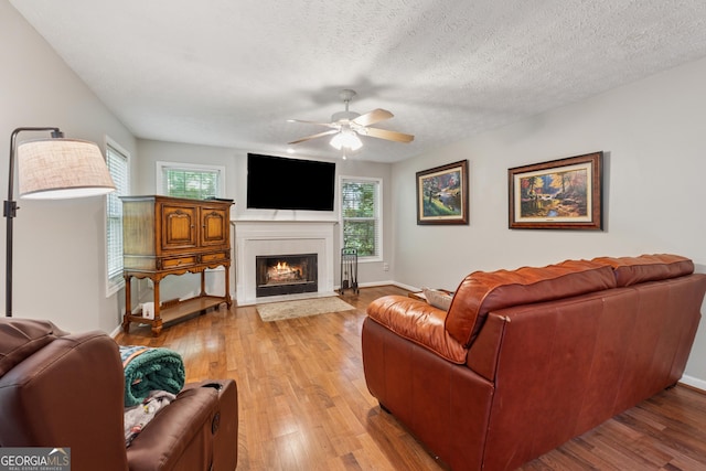 1679 Summit Place Way, Loganville, GA 30052 - living area with a ceiling fan, a lit fireplace, plenty of natural light, light wood-type flooring, and a textured ceiling