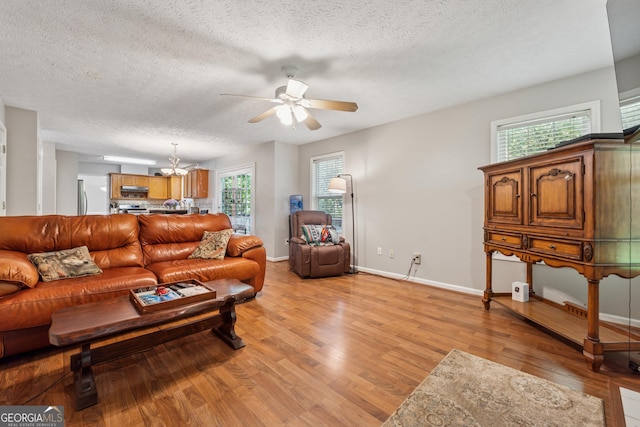 1679 Summit Place Way, Loganville, GA 30052 - living room with ceiling fan, light wood-style flooring, a textured ceiling, baseboards, and a chandelier