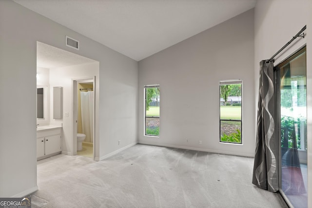 107 Linkside Dr, Saint Simons, GA 31522 - unfurnished bedroom featuring light colored carpet, baseboards, ensuite bath, and high vaulted ceiling