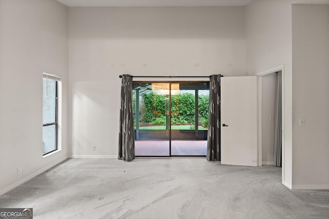 107 Linkside Dr, Saint Simons, GA 31522 - empty room featuring carpet, a towering ceiling, and baseboards