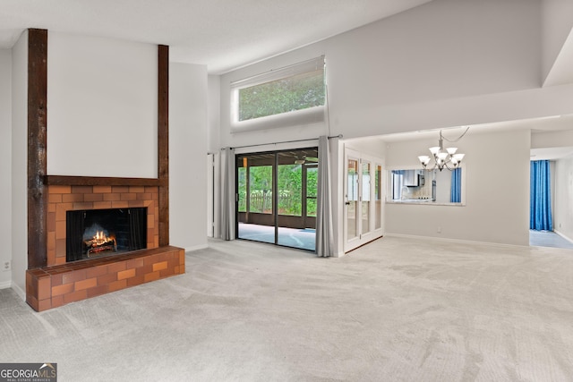 107 Linkside Dr, Saint Simons, GA 31522 - unfurnished living room featuring carpet floors, a towering ceiling, a chandelier, a brick fireplace, and baseboards