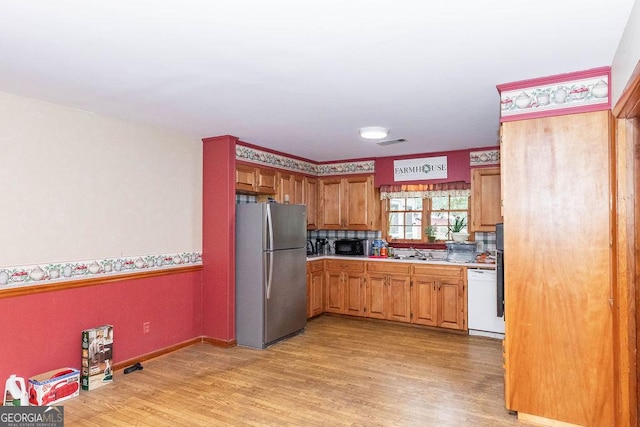 701 Log Landing Rd, Springfield, GA 31329 - kitchen with freestanding refrigerator, dishwasher, light wood-style flooring, light countertops, and a sink