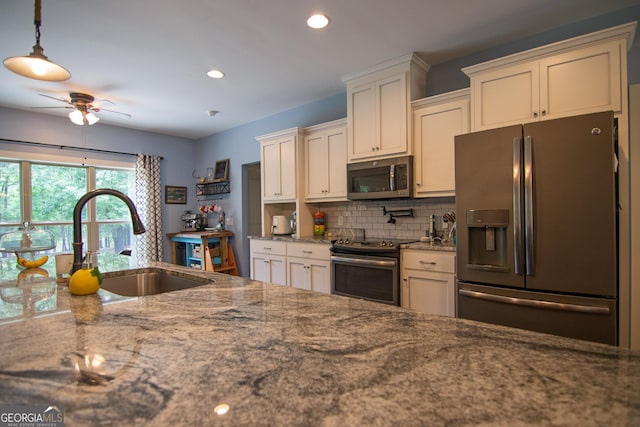 299 Savior Ln, Hamilton, GA 31811 - kitchen with appliances with stainless steel finishes, a sink, tasteful backsplash, a ceiling fan, and dark stone counters