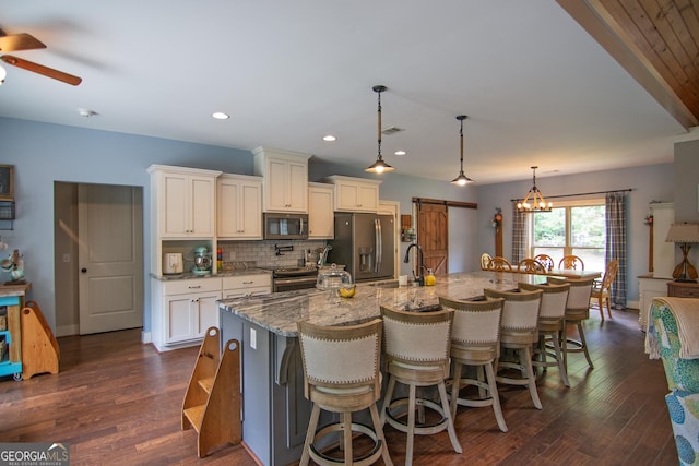 299 Savior Ln, Hamilton, GA 31811 - kitchen with appliances with stainless steel finishes, a ceiling fan, tasteful backsplash, light stone countertops, and a kitchen breakfast bar