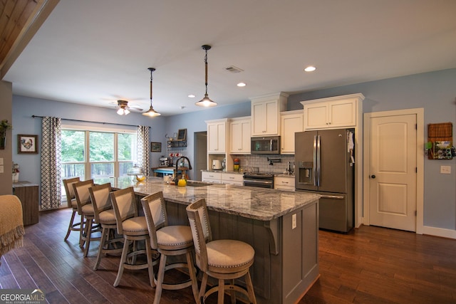299 Savior Ln, Hamilton, GA 31811 - kitchen featuring appliances with stainless steel finishes, a breakfast bar area, decorative backsplash, white cabinetry, and light stone countertops