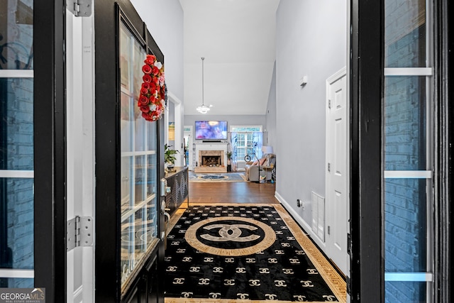 151 Dumar Ln, Hoschton, GA 30548 - foyer featuring wood finished floors, a fireplace with raised hearth, vaulted ceiling, and baseboards