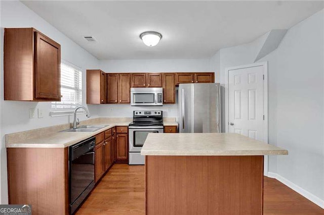 328 Oaktown Ct, Lawrenceville, GA 30044 - kitchen with appliances with stainless steel finishes, a sink, light countertops, light wood finished floors, and a kitchen island