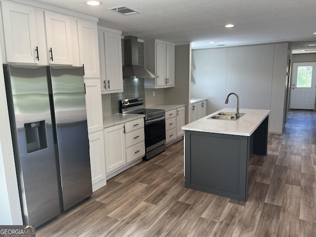585 Elmer Thrift Rd, Waycross, GA 31503 - kitchen with appliances with stainless steel finishes, wall chimney exhaust hood, a sink, wood finished floors, and light countertops