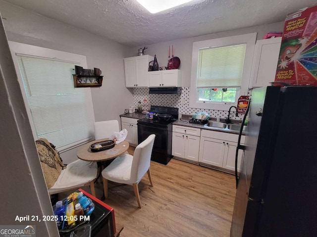 1336 Winton Ave, Macon, GA 31204 - kitchen with black range with electric stovetop, freestanding refrigerator, a sink, white cabinets, and a textured ceiling