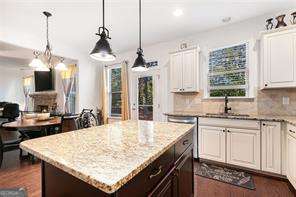121 Royal Sunset Dr, Dallas, GA 30157 - kitchen with light stone countertops, a kitchen island, white cabinetry, decorative light fixtures, and tasteful backsplash