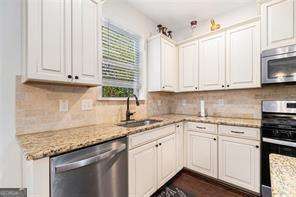 121 Royal Sunset Dr, Dallas, GA 30157 - kitchen featuring stainless steel appliances, a sink, decorative backsplash, and white cabinetry