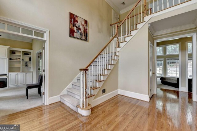 5980 Whitestone Ln, Suwanee, GA 30024 - stairs with crown molding, wood finished floors, and a towering ceiling