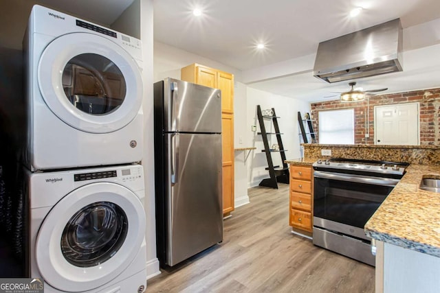 40 Daniel St SE, Atlanta, GA 30312 - kitchen featuring appliances with stainless steel finishes, wall chimney exhaust hood, stacked washer / drying machine, light wood-style flooring, and a ceiling fan