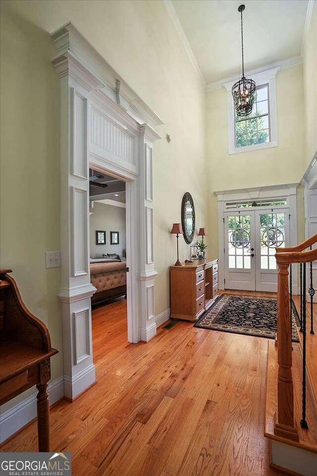 1917 Hearthstone Ct, Winder, GA 30680 - foyer entrance with french doors, a chandelier, light wood-type flooring, a high ceiling, and crown molding