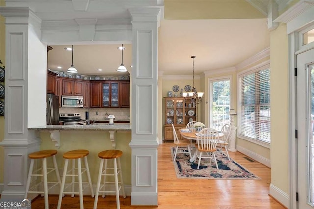 1917 Hearthstone Ct, Winder, GA 30680 - kitchen with stainless steel appliances, ornamental molding, backsplash, light wood-style flooring, and a breakfast bar area