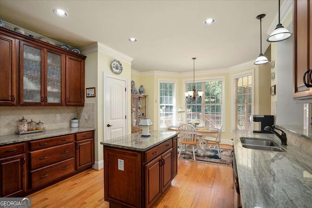 1917 Hearthstone Ct, Winder, GA 30680 - kitchen featuring a sink, light wood finished floors, a chandelier, tasteful backsplash, and crown molding