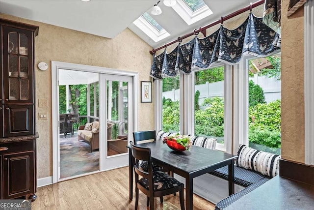 162 Daltree Ct, Marietta, GA 30068 - dining area with a skylight, plenty of natural light, light wood-type flooring, a textured wall, and high vaulted ceiling